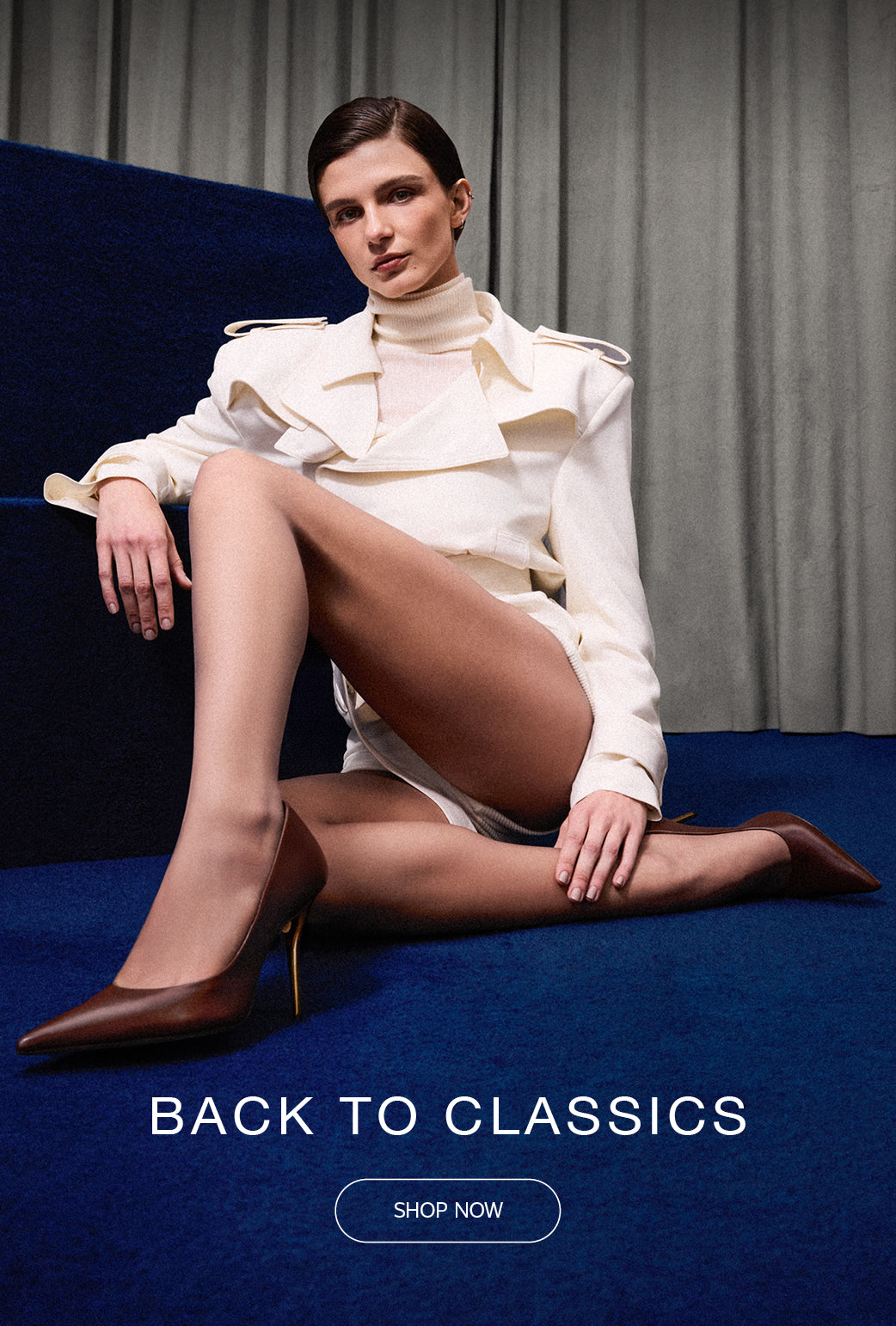Model wearing a white trench coat and brown classic pumps, seated on deep blue stairs against a gray curtain background. Text on image reads 'Back to Classics'.