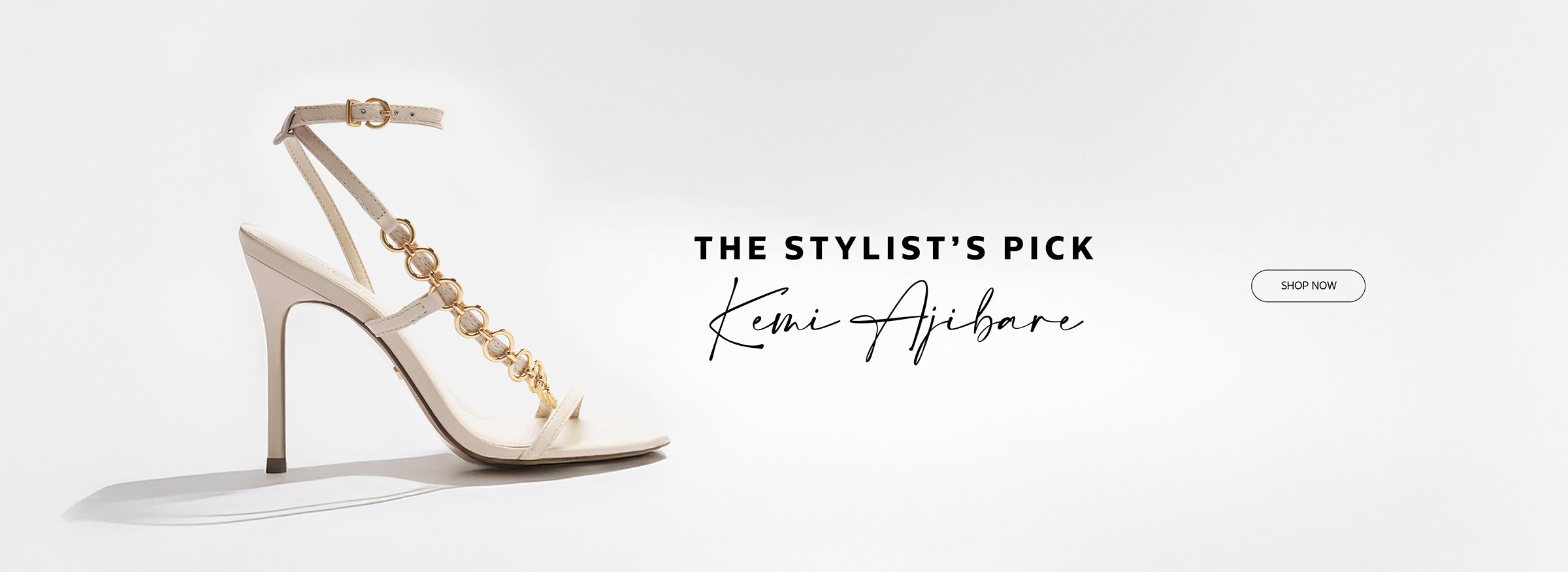 Elegant high-heeled sandal in off-white with gold chain-link detailing along the T-strap and ankle buckle, showcased as part of "The Stylist’s Pick" by Kemi Ajibare.