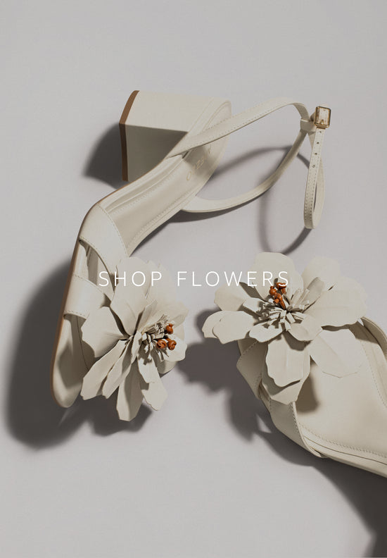 Anne Stiletto Sandal. The style features a high stiletto heel and a rounded toe. It has twisted gold and silver straps over the toes and another diagonal strap across the instep. With a buckle closure and a golden insole with the brand name engraved on it. The style shows the foot. 