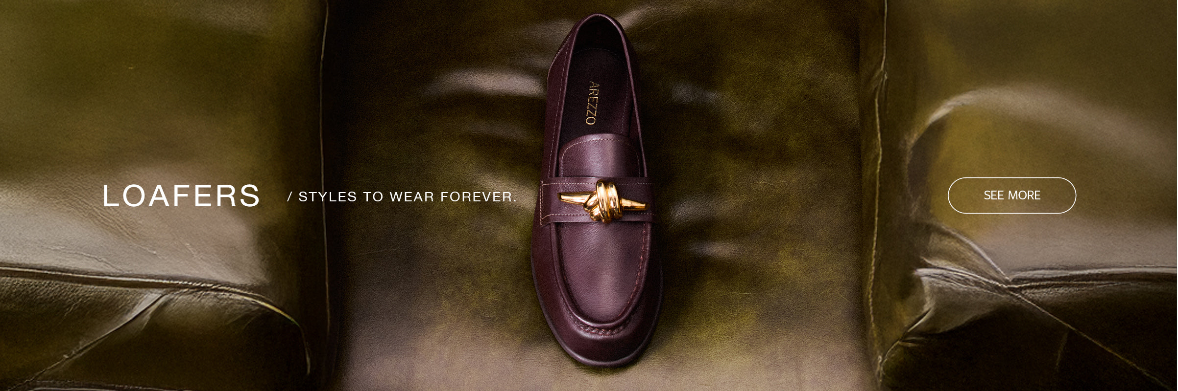 Single burgundy leather loafer with gold hardware detail from Arezzo, placed on a green leather armchair.