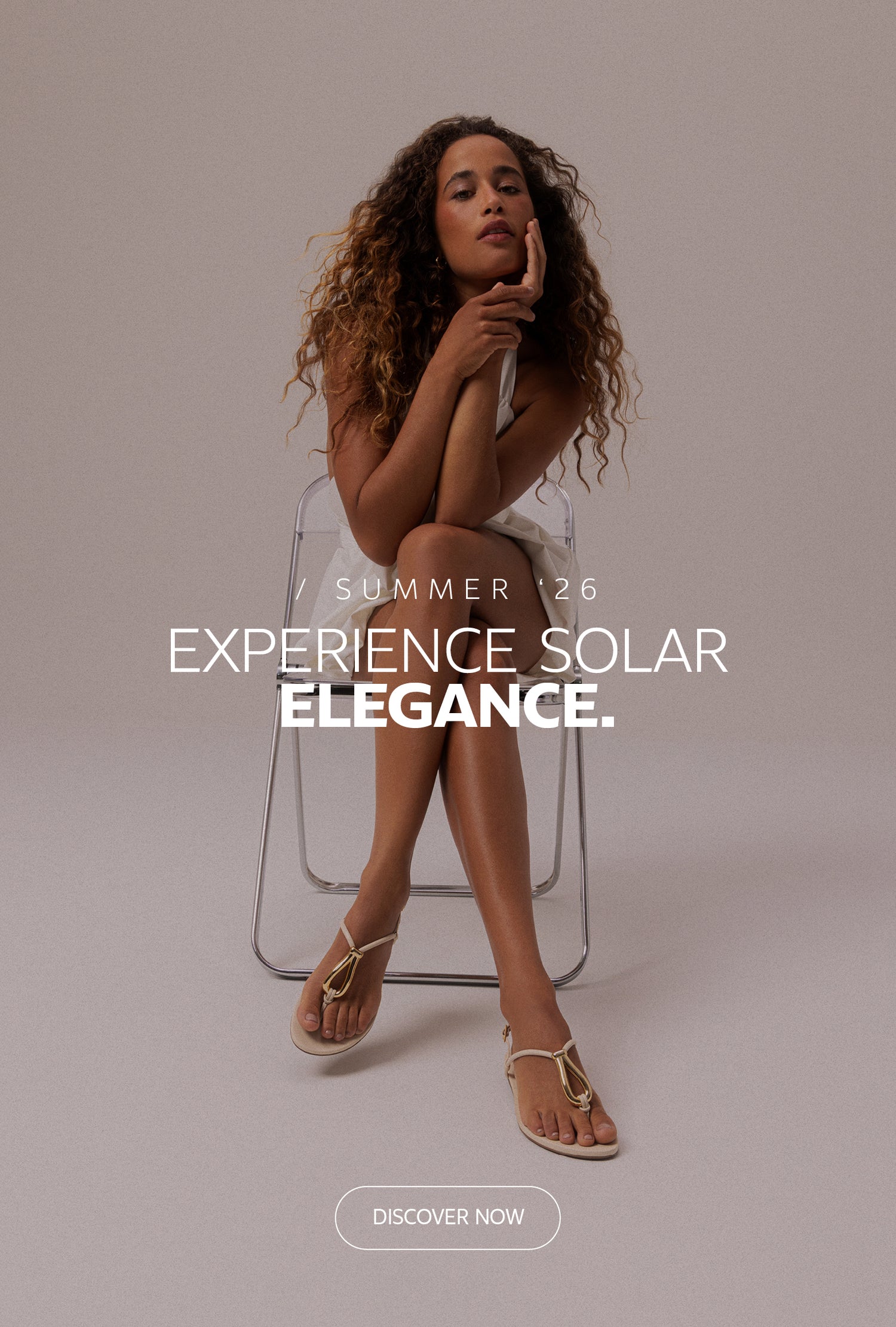 Summer ’26 campaign banner featuring brown leather sandals with gold metallic detail on the left and a seated model wearing white on the right, with the headline “Experience Solar Elegance” and a “Discover Now” CTA in the center.