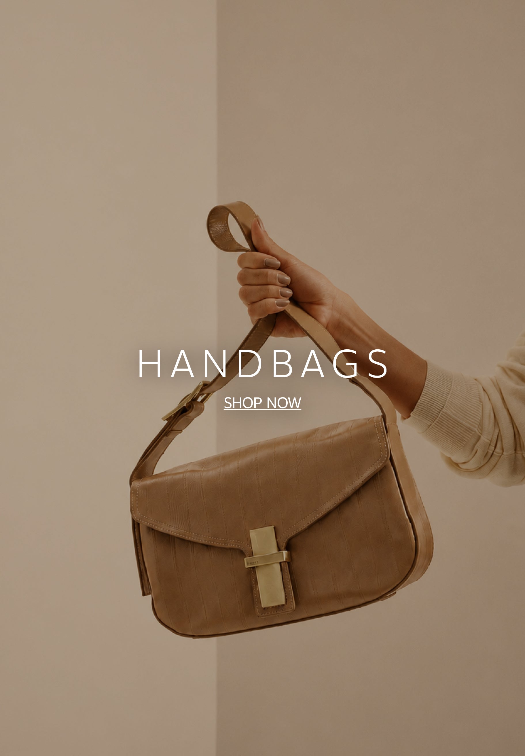A person's hand holding a tan leather shoulder bag by its strap against a minimalist beige wall. The handbag features a front flap closure with a rectangular gold-tone clasp. Centered white text reads 